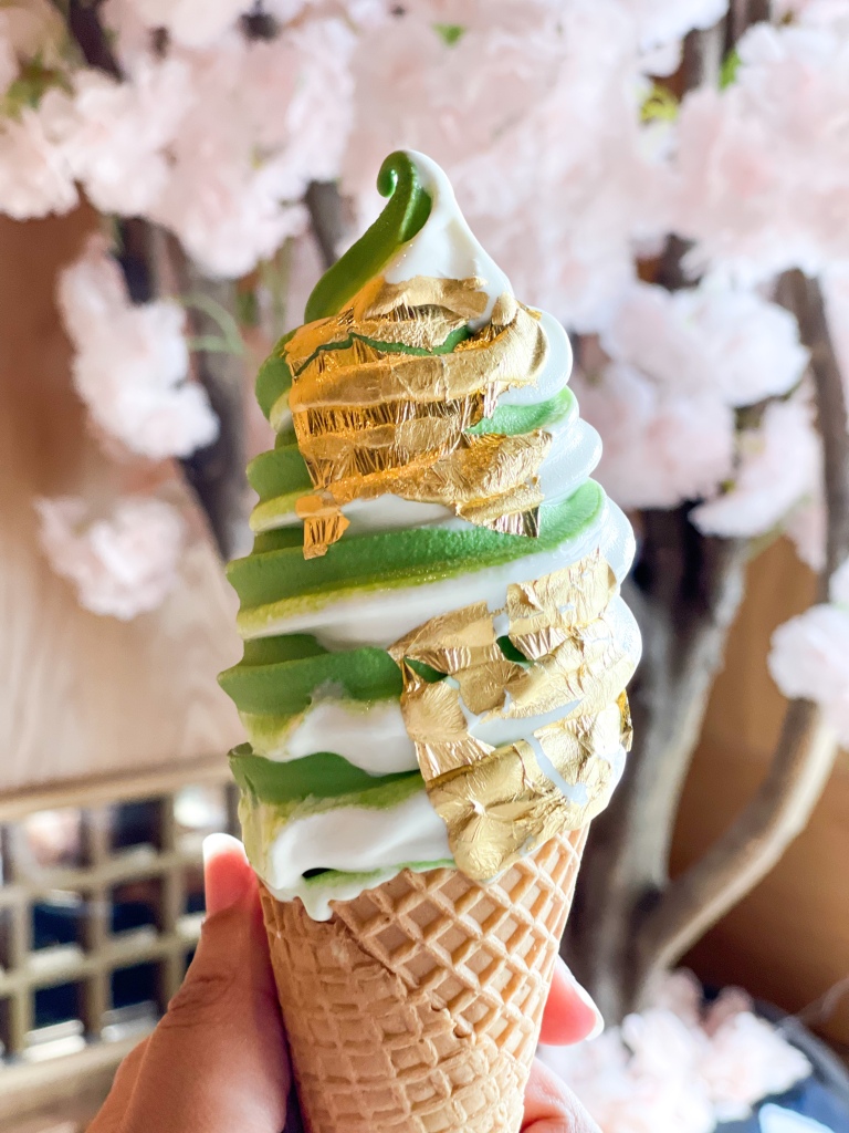 A hand holding ice cream from Kyoto Matcha, located in Maryland. The flavor is Matcha & Milk topped with gold flakes.