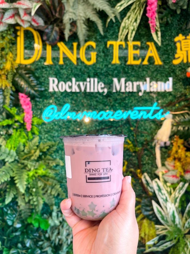 A hand holding blueberry milk tea from Ding Tea, which is a bubble tea shop in Rockville, Maryland