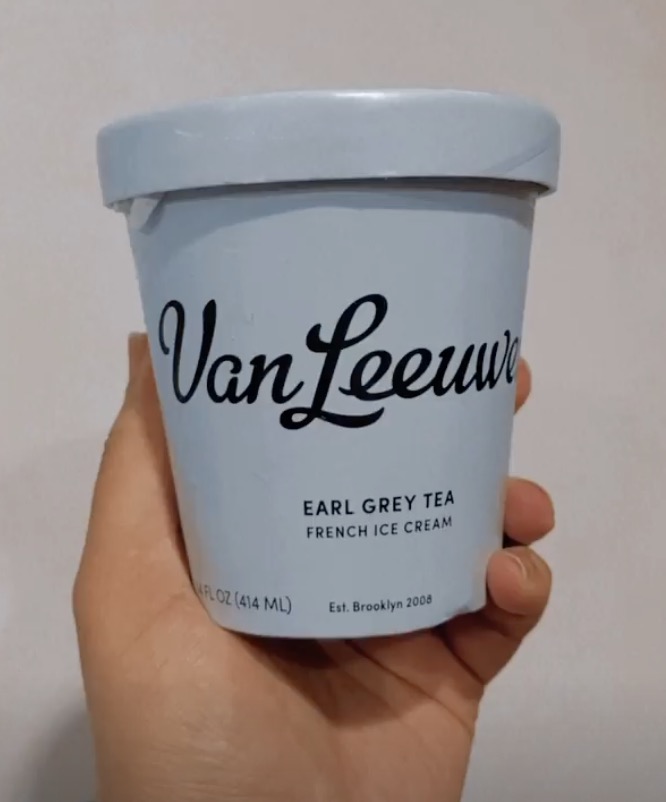 A hand holding a pint of Earl Grey Tea ice cream made by Van Leeuwen Ice Cream.